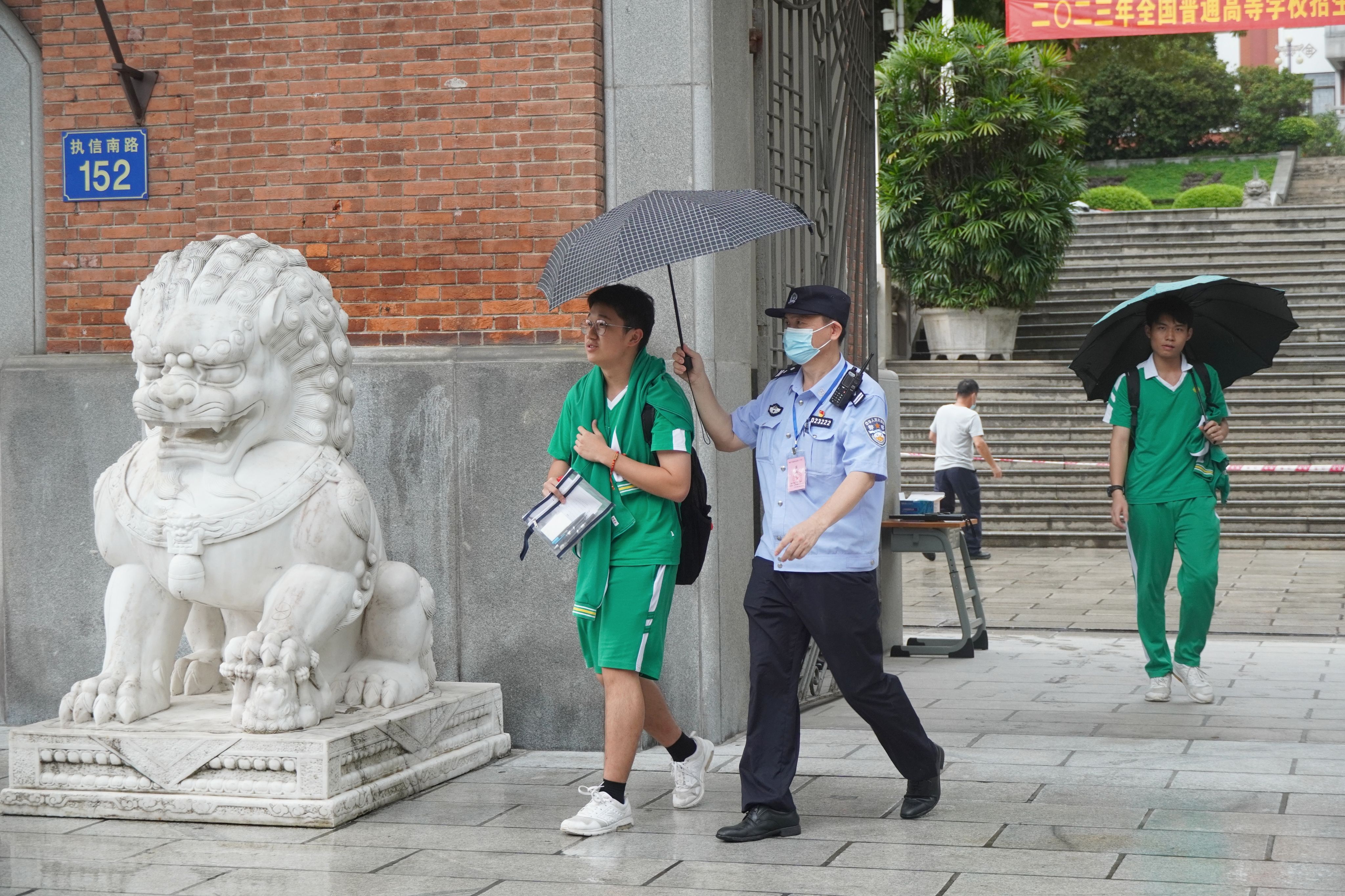 高考首日，省內(nèi)部分地區(qū)出現(xiàn)降水，民警撐傘護(hù)送考生。王雅蝶 攝